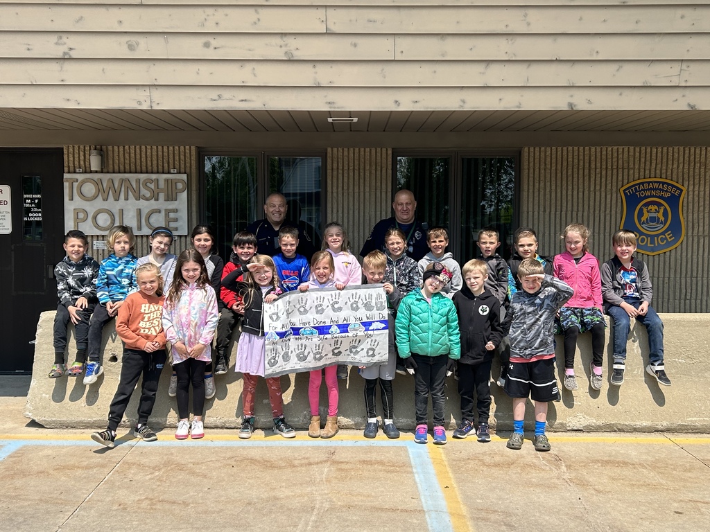 Students holding a thank you sign in front of the Police Station .